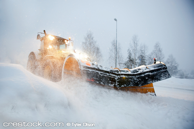 A snow plow clearing a road in winter